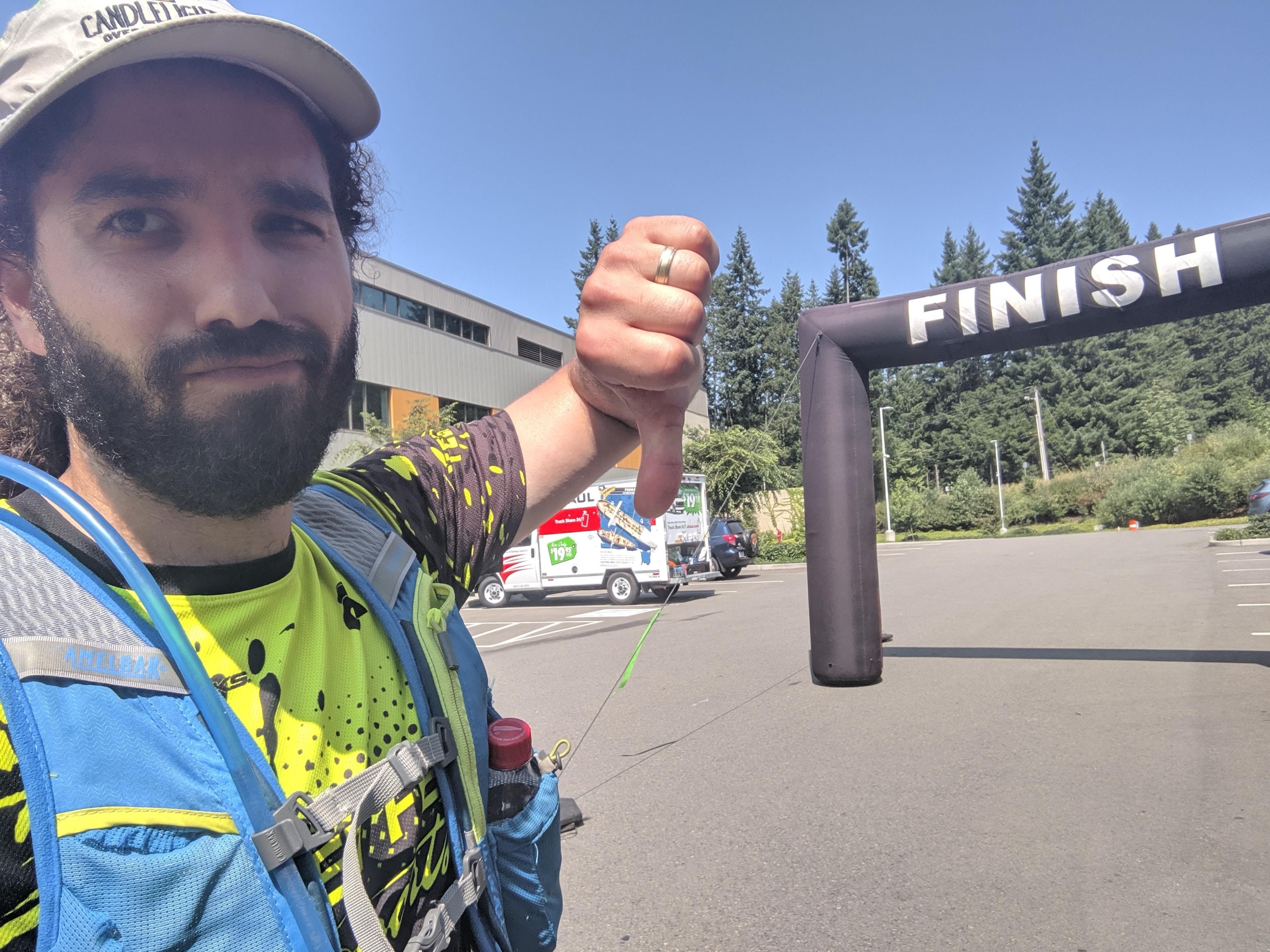 Selfie of me with a frown and giving a "thumbs down" hand sign, with the "Finish" inflatable archway behind me