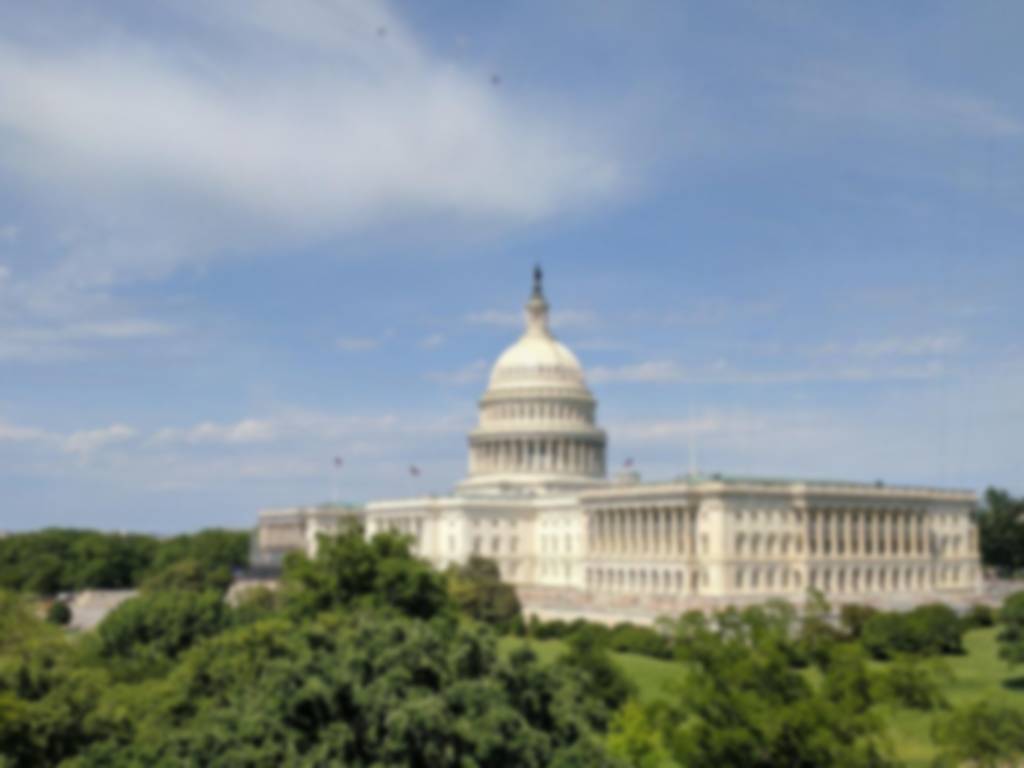 The US Capitol building surrounded by green trees and grass